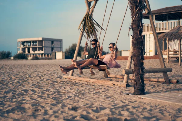 Jovem casal atraente balançando em seesaw na praia. — Fotografia de Stock
