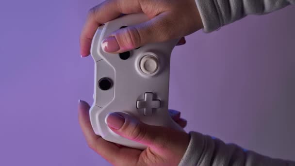 Руки з білим геймпадком на фіолетовому фоні. Вертикальне відео "Bomerangs" . — стокове відео