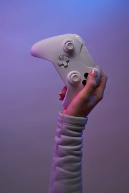 Menekşe arka planında beyaz oyun joystick 'i olan el.