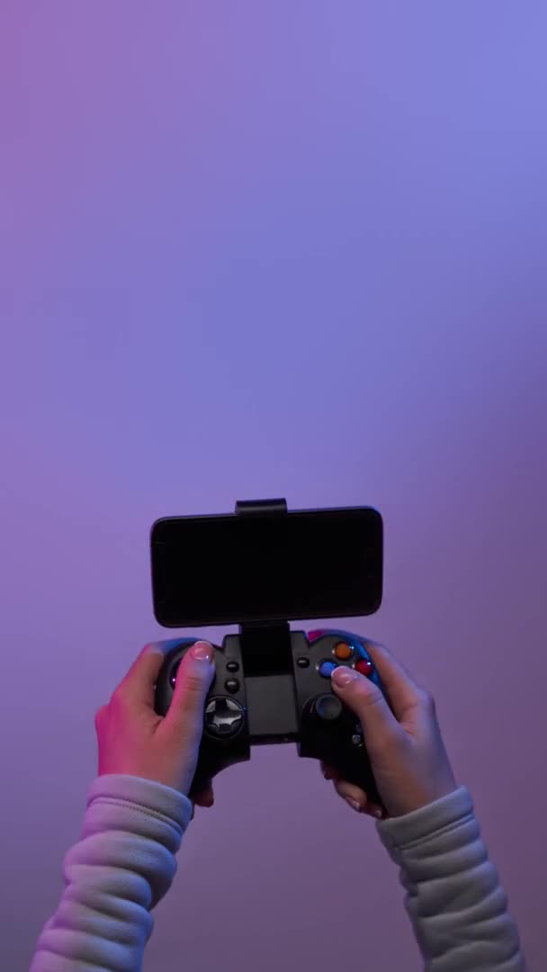 Hands with black gamepad on violet background. Bomerangs vertical video. — Stock Video