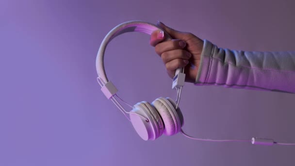 紫色の背景に白いヘッドフォンで手。Bomerangs垂直ビデオ. — ストック動画