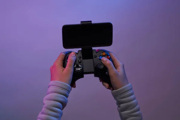 Hands with a game joystick on violet background. — Stock Photo, Image