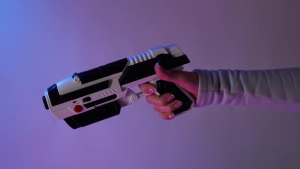 Kéz egy blaster játékok kiterjesztett valóság egy lila háttér. Bomerangs függőleges videó. — Stock videók
