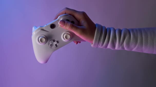 Hand mit weißem Gamepad auf violettem Hintergrund. Bomerangs vertikales Video. — Stockvideo