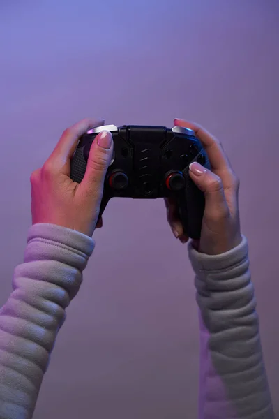 Manos con un joystick de juego sobre fondo violeta. — Foto de Stock
