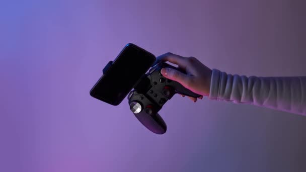 Hand with grey gamepad on violet background. Bomerangs vertical video. — Stock Video