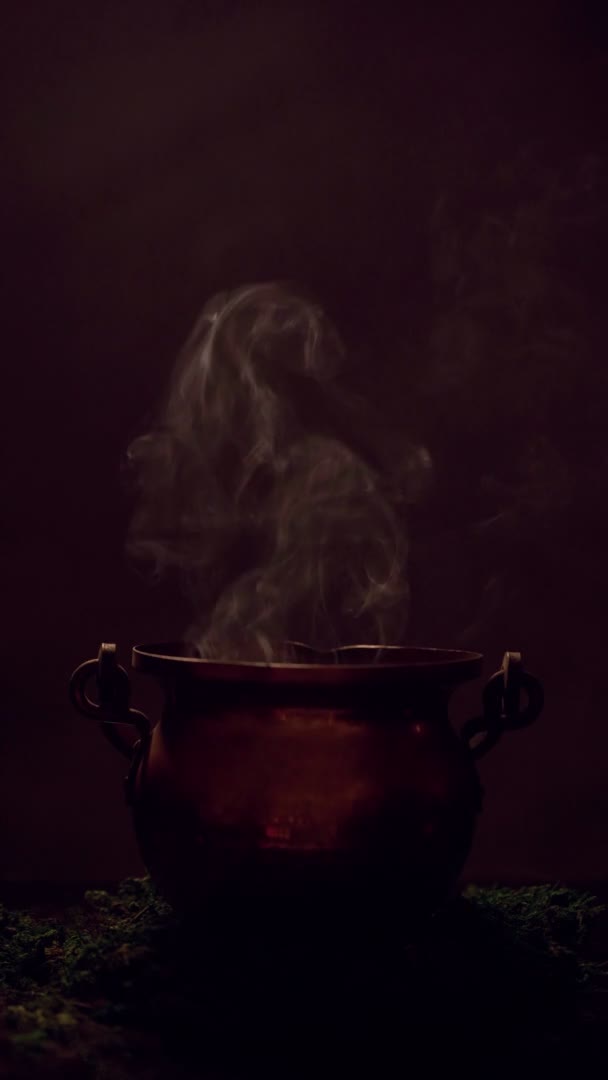 A boszorkány keze belenyomta a szemét a füstölgő üstbe. Függőleges videó. — Stock videók