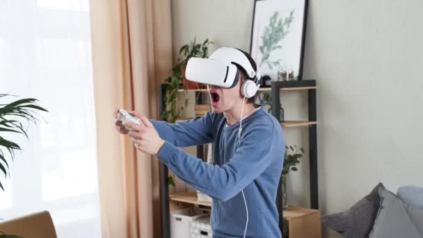 Человек играет в игру с гарнитурой виртуальной реальности и джойстиком — стоковое видео