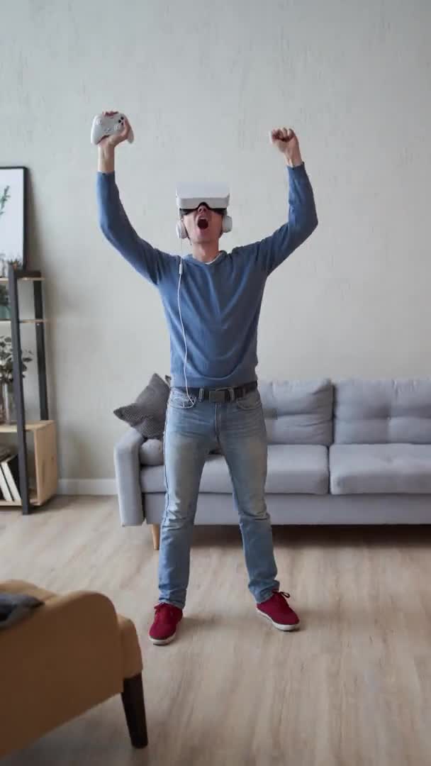 Человек играет в игру с гарнитурой виртуальной реальности и джойстиком. Вертикальное видео. — стоковое видео