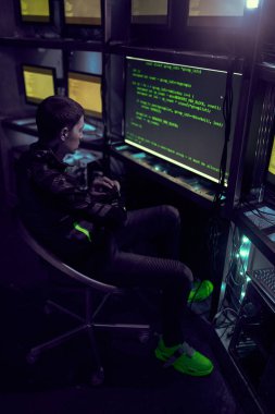 Hacker karanlık odada bilgisayar daktilo metniyle çalışıyor.
