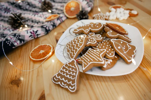 Вкусное домашнее рождественское печенье на тарелке с гирляндой и апельсинами. Дух нового года — стоковое фото