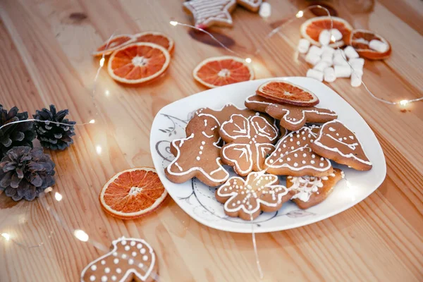 Köstliche hausgemachte Weihnachtsplätzchen mit Sahnehäubchen auf einem Teller mit Girlanden und Orangen. Geist des neuen Jahres — Stockfoto