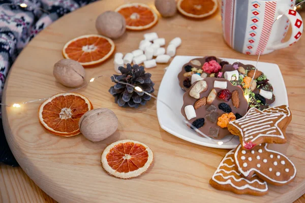 Köstliche hausgemachte Weihnachtsschokolade mit Zusatzstoffen auf einem Teller mit Girlanden und getrockneten Orangen, Marshmallows, Zapfen, Walnüssen. Geist des neuen Jahres — Stockfoto