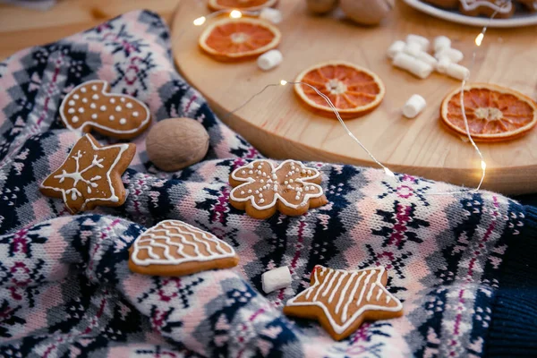 Strickpullover, Weihnachtsplätzchen, Girlanden, Marshmallows und getrocknete Orangen auf einem Holzkreis. Gemütliche Weihnachtskomposition — Stockfoto