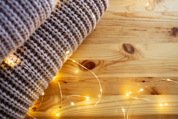 La pila de suéter se encuentra en una mesa de madera con guirnalda. Espacio para texto — Foto de Stock