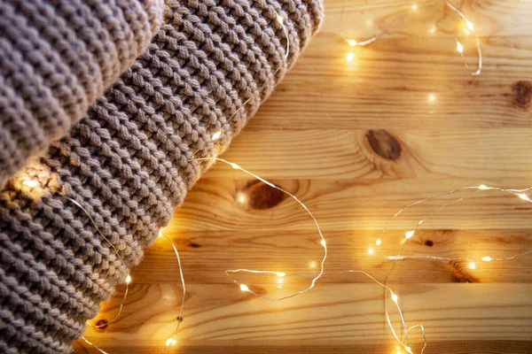 La pila de suéter se encuentra en una mesa de madera con guirnalda. Espacio para texto — Foto de Stock