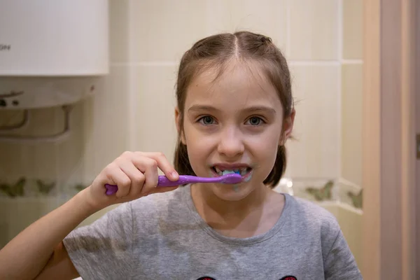Seorang gadis kecil menggosok giginya dengan sikat gigi. Konsep kesehatan anak, obat-obatan, pencegahan. Stok Lukisan  