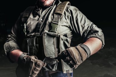 Taktik kıyafetli ve eldivenli asker koruyucu yelek giyiyor..