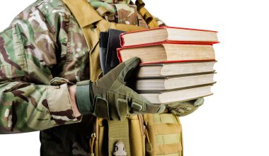 Üniformalı bir askerin beyaz arka planda kitap yığını tutarken çekilmiş resmi..