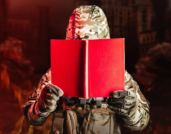 制服と鎧兜を着た兵士の写真が壊れた都市の背景に赤い本を開いた — ストック写真