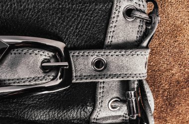 Süet arka planda duran metal kemerli deri çizmeli kadın fotoğrafı..