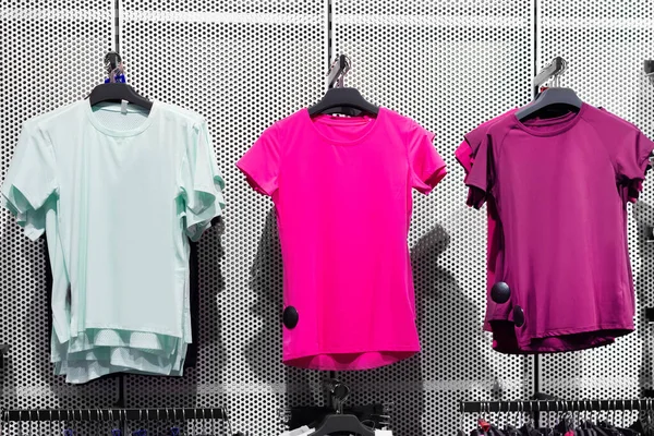Photo of multicolored sport t-shirts hanging on store rack.