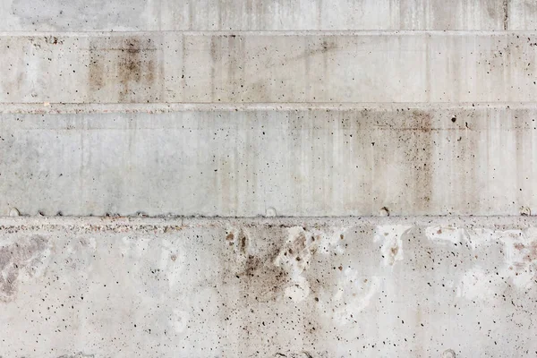 Texture photo of grey colored concrete wall made of horizontal blocks.