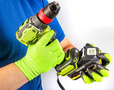 Kablosuz tornavida tutan ve beyaz arka planda akümülatör bataryasını değiştiren koruyucu eldivenli işçi erkek ellerinin izole edilmiş fotoğrafı..