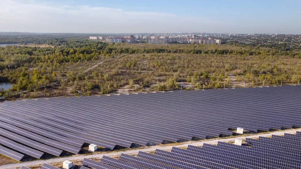 Güneş enerjisi çiftliği. Yüksek açı, şehirden uzak bir enerji çiftliğindeki yüksek güneş panelleri görüntüsü. hava görünümü