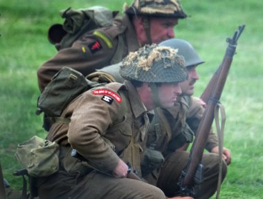 İkinci Dünya Savaşı sahnesini canlandıran oyuncular duman, alev ve boş fişeklerle sahneleniyor. İngiliz askerleri.