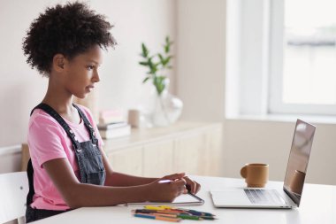 İnternette çalışan sevimli küçük bir kız. Çocuk evde dizüstü bilgisayar çizip kullanıyor. Eğitim, teknoloji, iletişim, gelecek, uzaklık öğrenme, ev ödevi, liseli çocukların yaşam tarzı kavramı