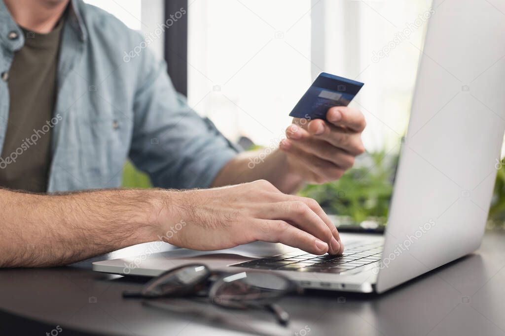 man using credit card to pay online with laptop 