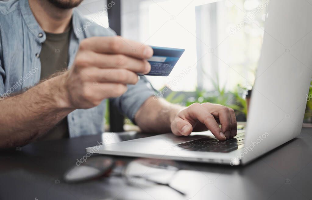 Man hand holding credit card and using laptop in office, Businessman or entrepreneur working on computer making payment, Online shopping, e-commerce, internet banking, spending money concept