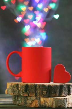 Tahta masada kalbi ve kalp şeklinde bokeh olan bir fincan kahve.
