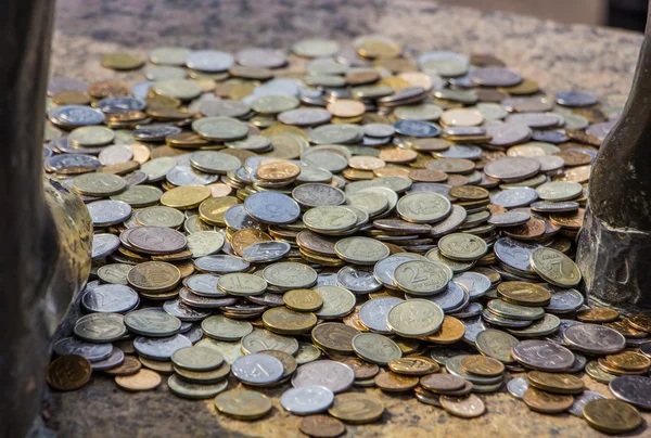 Verschillende munten aan het standbeeld voeten Rechtenvrije Stockfoto's