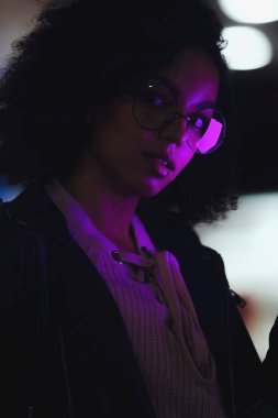 Genç, kıvırcık, Afro-Amerikan kızın portresi. Gece şehir ışıkları. Neon aydınlatması