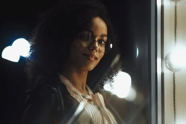 Fashionable woman on urban city street at night. Beautiful african american woman with black curly hair