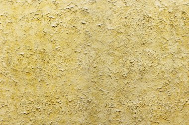 Kaba yüzey detaylarıyla desenli sarı alçı duvar.