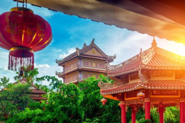 Kırmızı fenerli ve yemyeşil yapraklı geleneksel Asya tapınağı..