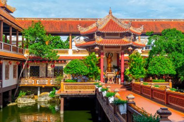 Gökyüzü altında süslü mimarisi ve gür yeşilliği olan geleneksel Asya tapınağı..