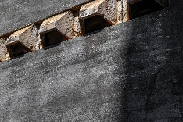 Gölge ışığında dikdörtgen delikli endüstriyel gri beton duvar.