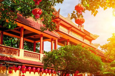 Kırmızı fenerleri ve güneş ışığıyla aydınlatılmış mimarisi olan geleneksel Asya tapınağı.
