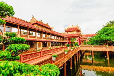 Yeşillik ve dekoratif mimarisi olan sakin bir göletin kenarındaki geleneksel Vietnam tapınağı..