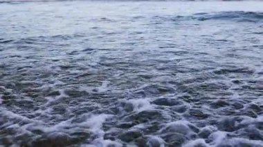 Dinamik okyanus dalgaları altın saat boyunca kumlu sahilde yavaşça çekiliyor.