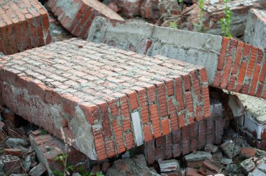 kırmızı tuğla duvarların parçaları çimlerin üzerinde çöplüğün arasında.