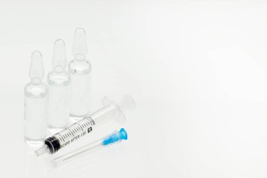 Cam ilaç ampulleri sıvı ve plastik şırınga ile beyaz arka planda izole edilmiş.