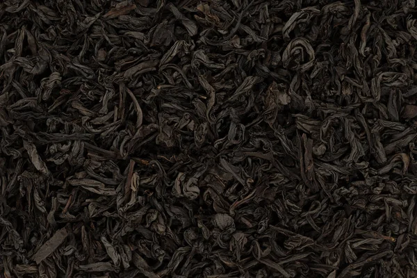 Dry black tea leaves as a background. Close up, top view