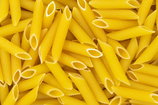 生のペンネのリゲートパスタの食感の背景 フラットなスタイル 伝統的なイタリア料理 — ストック写真