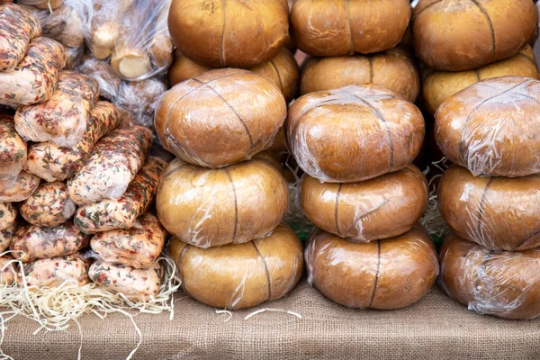 Various smoked Adyghe cheese in packs and in bulk on market counter — Stock Image Various Smoked Adyghe Cheese Packs Bulk Market Counter Stock Photo