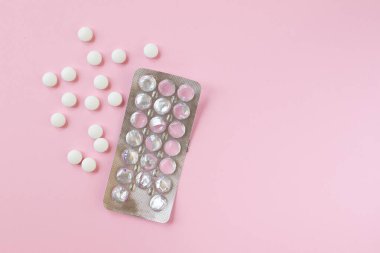 Pakette beyaz ilaç hapları var ve pembe bir arka planı yok. Üst Manzara. Düz yatıyordu. Tıp konsepti.